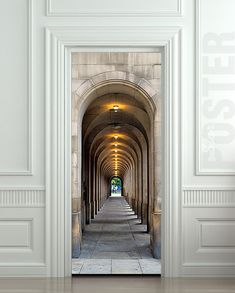 an archway leading into a building with light at the end and stone flooring on both sides