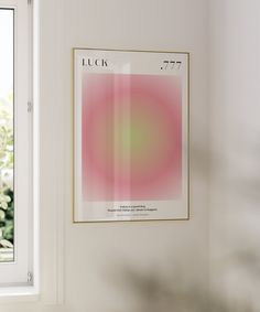 a pink and green poster hanging on the wall next to a window with a potted plant in it