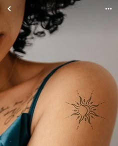 a woman with a sun tattoo on her left arm and right arm behind her head