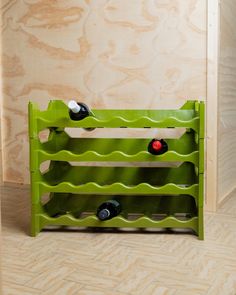 a green wine rack sitting on top of a wooden floor