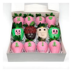 a box filled with lots of pink and green decorated strawberries next to each other