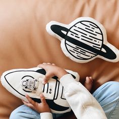 a child is holding a stuffed toy in front of a pillow with an image of saturn on it