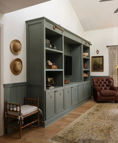 a living room with green bookcases and leather chairs in front of a window