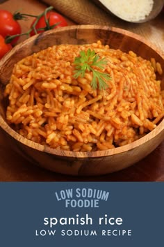 a wooden bowl filled with spanish rice on top of a table next to some tomatoes