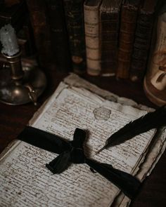 an old book with black ribbon tied around it on top of a table next to books