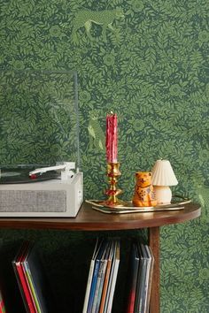 a table topped with books and a red candle sitting on top of a wooden table