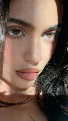 a close up of a woman's face with long dark hair and blue eyes