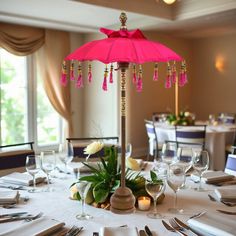 the table is set with silverware and pink umbrella