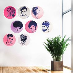 a potted plant sitting in front of a wall with different colored portraits on it