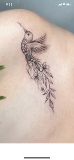 the back of a woman's stomach with a hummingbird tattoo on it, and flowers