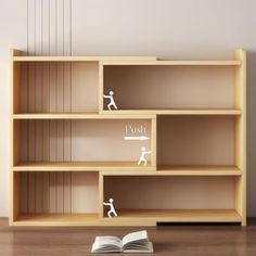 an open book is sitting on the floor next to a bookshelf with two figures