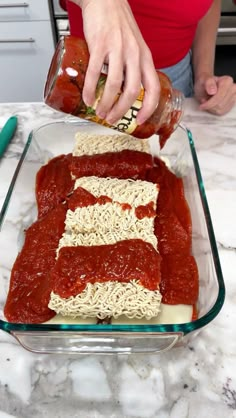 a person pouring sauce over noodles in a casserole dish