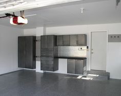 an empty garage with lots of cabinets and lights hanging from the ceiling in front of it