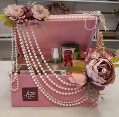 a pink purse with pearls and flowers on it sitting on top of a white table