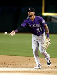 a baseball player throwing a ball on top of a field with his glove in the air