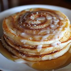 a stack of pancakes covered in syrup on a white plate