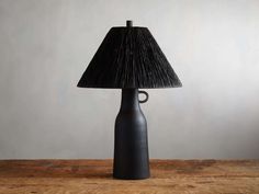 a lamp that is sitting on top of a wooden table next to a gray wall