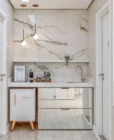 a kitchen with marble counter tops and white cabinets, along with wooden flooring that matches the walls