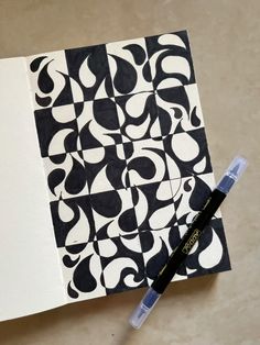 a pen sitting on top of a piece of paper with black and white designs on it