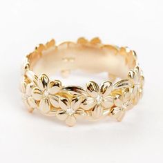 a yellow gold ring with flowers and diamonds on the inside, sitting on a white surface