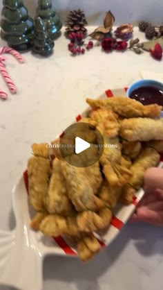 someone is dipping sauce on fried food in a bowl with candy canes behind them