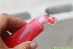 a hand holding a small red bottle with something in it