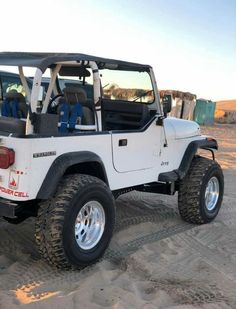 a white jeep is parked in the sand