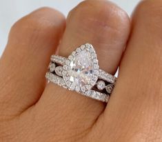 a woman's hand with two wedding bands and a diamond ring on her finger