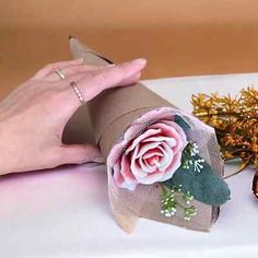 a person holding a flower on top of a roll of paper next to other flowers