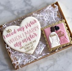 two decorated cookies in a gift box on a marble counter top, with the words mean my sister when i marry my mother