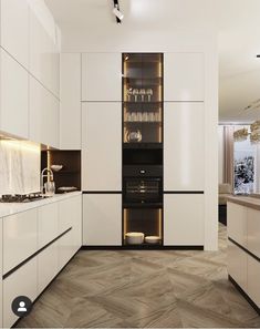 a modern kitchen with white cabinets and marble counter tops, along with wooden flooring