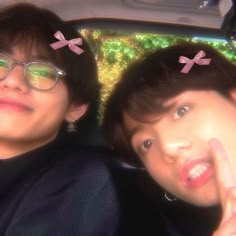 two people sitting in the back seat of a car with pink bows on their heads