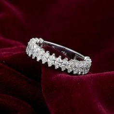 a diamond ring sitting on top of a red velvet surface, with the band partially covered in diamonds