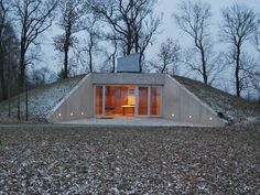 an unusual house in the woods is lit up at night