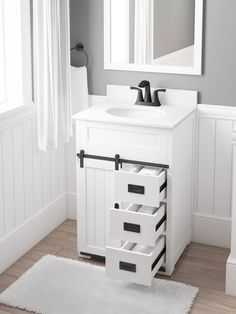 a white bathroom vanity with drawers under a mirror