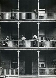 an old black and white photo of people on balconies in front of a building