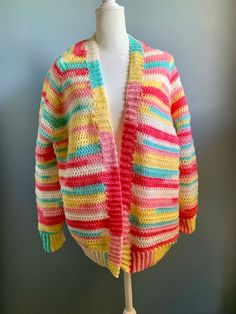 Handmade crocheted cardigan sweater is a vibrant stripe pattern. The long sleeves are trimmed with a ribbed cuff. The neck and bottom edge are also rib trimmed. Size is a generous medium. Made of acrylic yarn and machine washable. Reshape and lay flat to dry. Spring Multicolor Knitted Cardigan, Spring Multicolor Knit Outerwear, Spring Striped Chunky Knit Sweater, Multicolor Long-sleeved Sweater Coat For Spring, Multicolor Long Sleeve Sweater Coat For Spring, Cozy Striped Cardigan For Spring, Cozy Striped Spring Cardigan, Striped Long-sleeved Cardigan For Spring, Colorful Knit Cardigan For Spring