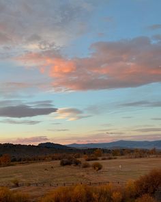 the sky is pink and orange as the sun sets in the distance with mountains in the background