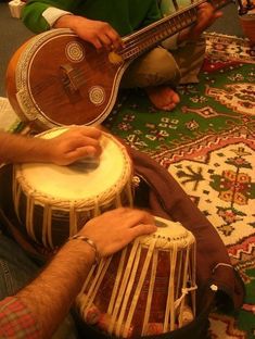 two men are sitting on the floor playing musical instruments