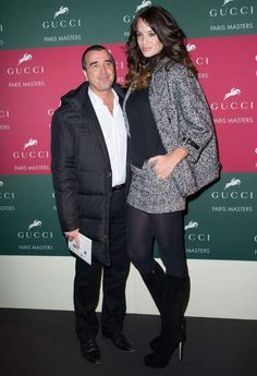 a man and woman standing next to each other in front of a red carpeted wall