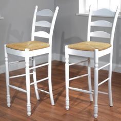 two white wooden chairs sitting next to each other on top of a hard wood floor