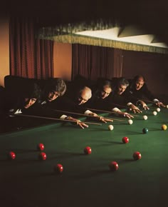 eight ball players are lined up on the green pool table with their cues in hand