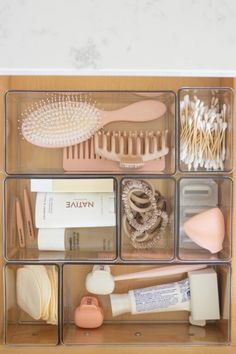 an organized drawer filled with beauty products and hairbrushes on top of a wooden table