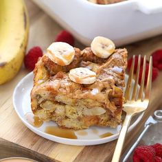 a piece of cake on a plate with raspberries and bananas