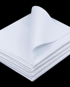 white folded napkins stacked on top of each other in front of a black background