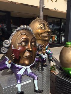 three large golden and purple masks on display in front of a store