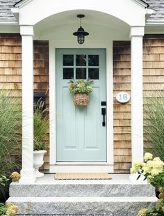 a blue front door with a basket on the side and flowers in pots next to it