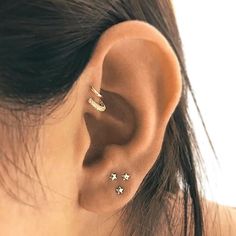 a close up of a person wearing gold ear piercings with stars on the back of their ears