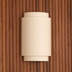 a white cylindrical light fixture mounted on a wooden wall