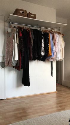 an organized closet with clothes hanging on rails